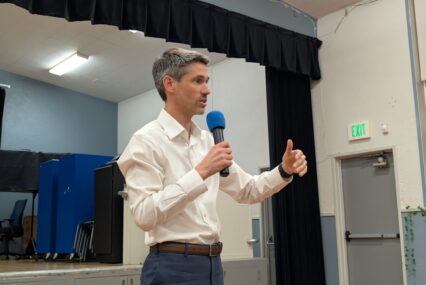 A man in a white collar shirt holding a microphone
