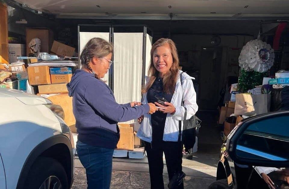 Two women stand in a driveway