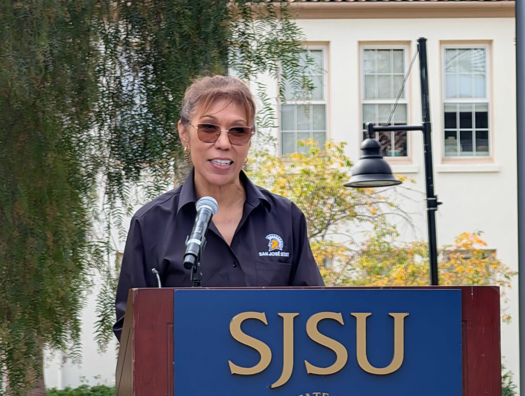 A woman standing at a podium on a college campus in San Jose, California